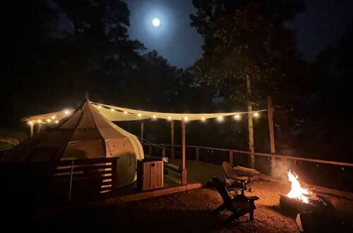 campsite at night with the moon and a fire in the fire pit